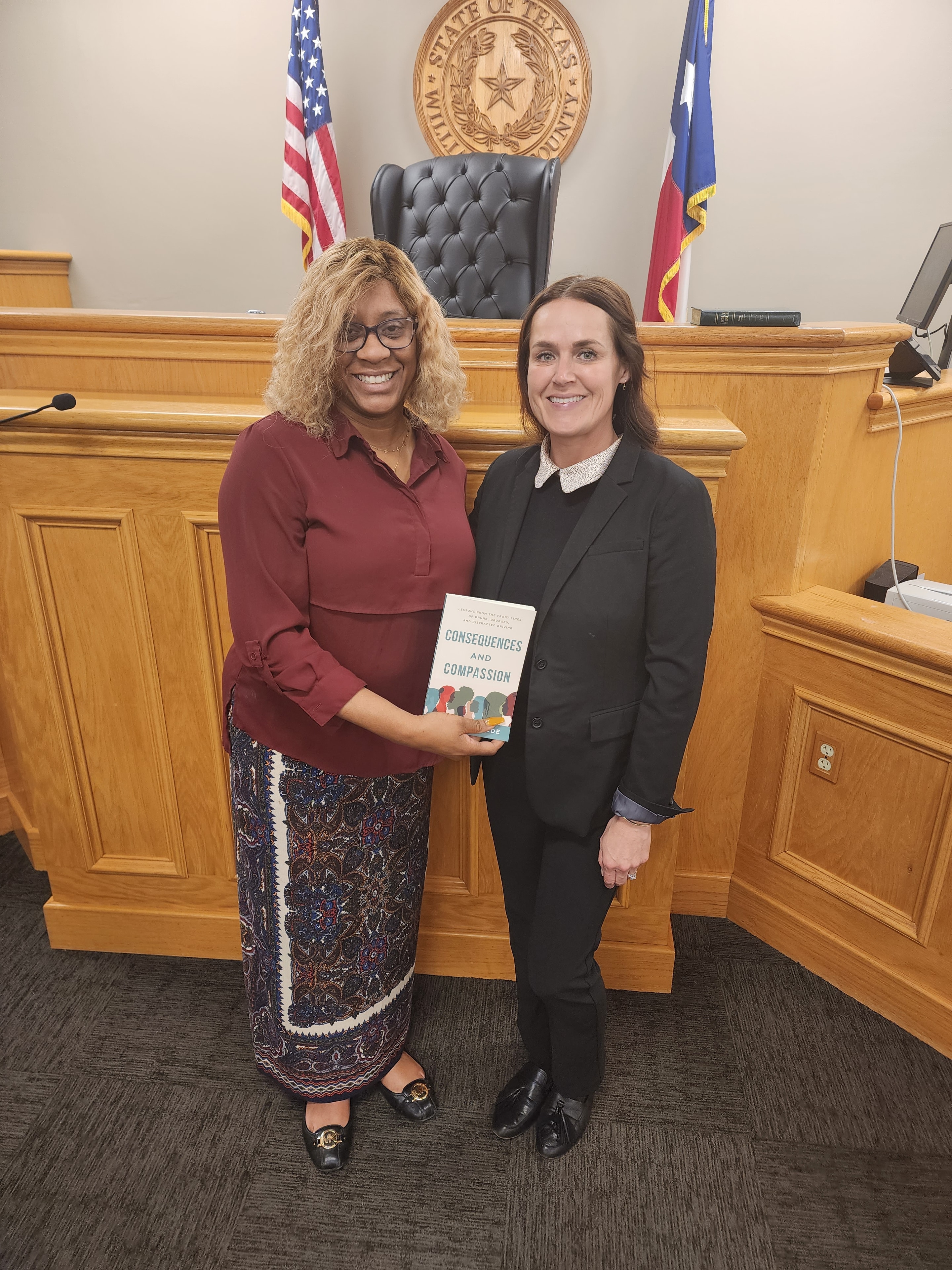 LaDonna Claude with official at Texas courthouse holding Consequences and Compassion